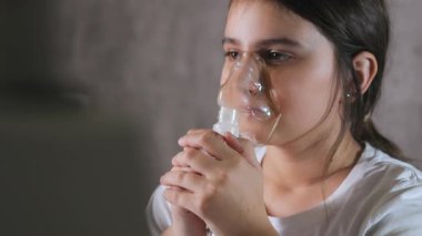 Nefes alan tıbbi maske takan küçük bir kız. Kız solunum yapıyor. Solunum hastalıklarının tedavisi için. Nefes alan tıbbi maske takan küçük bir kız.. 