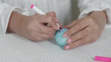 Paskalya kutlaması için paskalya yumurtası süsleyen bir kızın yakın çekimi. Paskalyayı kutluyoruz. Aile Paskalya yumurtalarını boyar..