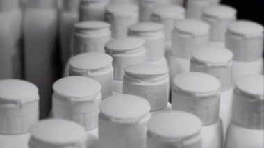 Fabrikadaki bir taşıma bandında hareket eden beyaz plastik şişelerin yakın çekimi. Kozmetik fabrikası. Kozmetik ürünleri için plastik şişe üreten bir fabrika..