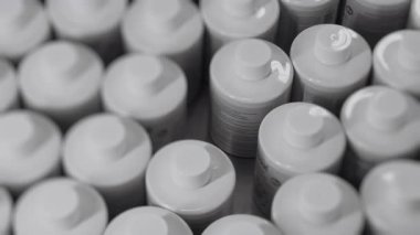 Fabrikadaki bir taşıma bandında dönen beyaz plastik şişelerin yakın çekimi. Kozmetik fabrikası. Kozmetik ürünleri için plastik şişe üreten bir fabrika..