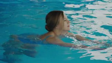 Mavi mayolu sarışın kız spa merkezinde havuzda yüzüyor. Bilardodaki genç kadın. Spa merkezi konsepti. Sağlık Merkezi.