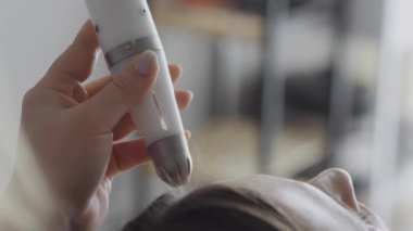 Eldivenli bir kozmetik uzmanı kozmetoloji kliniğinde genç bir kadının yüzünü vakumla temizliyor. Modern kozmetoloji kliniklerinde nemlendirici ve gençleştirici donanım prosedürleri.