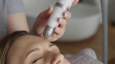 Eldivenli bir kozmetik uzmanı kozmetoloji kliniğinde genç bir kadının yüzünü vakumla temizliyor. Modern kozmetoloji kliniklerinde nemlendirici ve gençleştirici donanım prosedürleri.