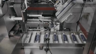 Kozmetik fabrikasında karton kutularda kremalı tüpler paketleme. Bir fabrikada kozmetik üretimi. Bir santralde otomatik paketleme hattı.
