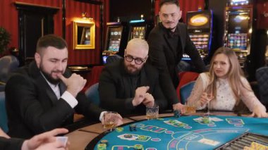 Erkekler ve kadınlar kumarhanede oynamak için masada oturuyorlar. Kumarhanede oyun masasında oynayan bir grup insan. Kumar konsepti.