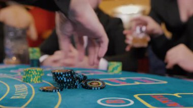 Krupiye kumar masasında bir kumarhanede fiş dağıtıyor. Kumarhanede oyun masasında oynayan bir grup insan. Kumar konsepti.