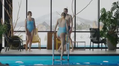 Mayolu bir adam ve iki kadın karlı dağlardaki bir havuzda spa merkezinde dinleniyorlar. Dağlardaki spa merkezi. Bir kız havuza iniyor..