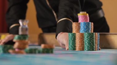 Kumarhanedeki kumar masasının üzerinde bir yığın fiş taşıyan bir krupiyenin elleri. Kumarhanede oynama fikri. Kumarhanede büyük bahisler.