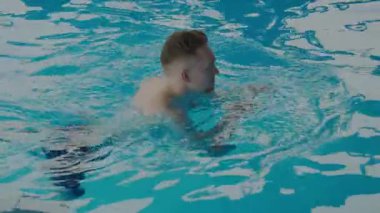 Genç bir adam spa merkezindeki bir havuzda yüzüyor. Bilardodaki genç kadın. Spa merkezi konsepti. Sağlık Merkezi.