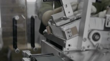 İçinde ürünler, ilaçlar, kozmetik kremler olan kutulara talimatlar olan broşürlerle otomatik olarak besleniyor. Kozmetik fabrikası. Farmakoloji fabrikası.