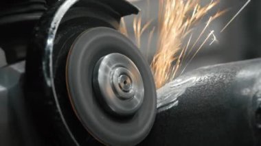 Metal fabrikasında çalışan bir işçi metali işliyor. Öğütücüden kıvılcımlar çıkıyor. Metal üretim fabrikası.