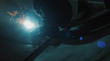 Koruyucu maskeli profesyonel bir kaynakçı büyük bir tankın içinde çalışır. Metal bir inşaat fabrikası. Kocaman bir silindirde kaynak izleri var. Endüstriyel ısıtma kazanı üretimi. c Fabrikası.