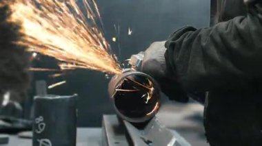 Metal fabrikasında çalışan bir işçi metali işliyor. Öğütücüden kıvılcımlar çıkıyor. Metal üretim fabrikası.