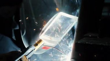  Koruyucu maskeli bir fabrikada çalışan bir işçi metal bir yapıyı kaynaklıyor. Metal yapılar üreten bir fabrika. Kaynak metalinden kıvılcımlar. Endüstriyel üretim. 