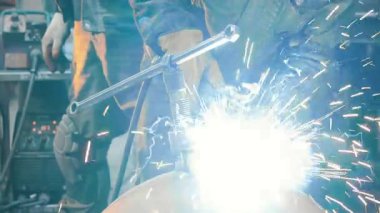  Koruyucu maskeli bir fabrikada çalışan bir işçi metal bir yapıyı kaynaklıyor. Metal yapılar üreten bir fabrika. Kaynak metalinden kıvılcımlar. Endüstriyel üretim. 