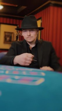 Poker oynayan sakallı bir adam. Oyuncu kumarhanede poker oynar. Dikey video.