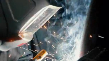  Koruyucu maskeli bir fabrikada çalışan bir işçi metal bir yapıyı kaynaklıyor. Metal yapılar üreten bir fabrika. Kaynak metalinden kıvılcımlar. Endüstriyel üretim. 