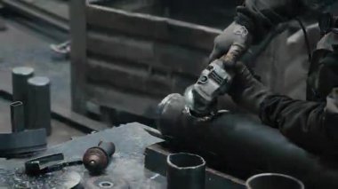 Metal fabrikasında çalışan bir işçi metali işliyor. Öğütücüden kıvılcımlar çıkıyor. Metal üretim fabrikası.