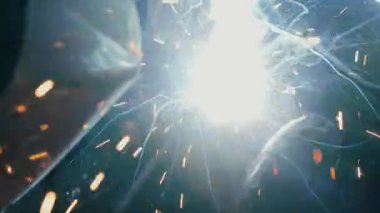 Koruyucu maskeli bir fabrikada çalışan bir işçi metal bir yapıyı kaynaklıyor. Metal yapılar üreten bir fabrika. Kaynak metalinden kıvılcımlar. Endüstriyel üretim. 