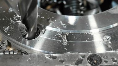 Matkap ucu, metal bir atölyede delik açıyor. Endüstriyel bir fabrikanın torna tezgahında çelik bir ürün işleniyor..
