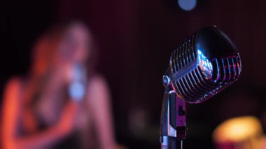 Karaoke kulübündeki klasik mikrofonun yakın çekimi, arka planda dans eden kız. Karaoke kulübü partisi.