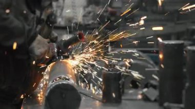 Metal fabrikasında çalışan bir işçi metali işliyor. Metal kıvılcımları ağır sanayi fabrikasında üretiliyor. Metal öğütme işlemi. Çelik fabrikası..