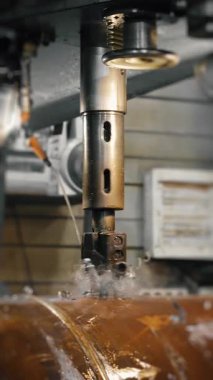 Matkap soğutmalı otomatik endüstriyel sondaj makinesi. Metal yapı fabrikasında kalın çelik borularda delik açmak. Endüstriyel ısıtma kazanı üretimi. Dikey video.