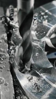 Matkap ucu, metal bir atölyede delik açıyor. Endüstriyel bir fabrikadaki torna tezgahında çelik bir ürün işleniyor. Dikey video.