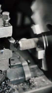 Torna bir atölyede demir bir atölye işidir. Metal kesme makinesi yuvarlak çelik çubuğa konik bir şekil verir. Bir endüstriyel metal işleme tesisi. Dikey video.