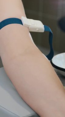 Bir hemşire hastasının kolunu damardan kan almaya hazırlar. Doktor hastadan analiz için kan alır. Hastanın kan analizi. Dikey video.