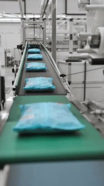 Paketlenmiş makronlar taşıyıcı boyunca hareket eder. Modern makarna fabrikası. Makarna üretimi için modern otomasyon fabrikası. Fabrikadaki modern ekipmanlar. Modern gıda endüstrisi. Dikey video.