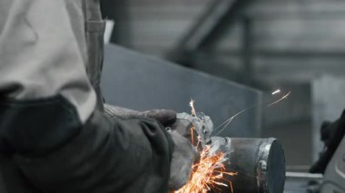 Metal fabrikasında çalışan bir işçi metali işliyor. Metal kıvılcımları ağır sanayi fabrikasında üretiliyor. Metal öğütme işlemi. Çelik fabrikası..