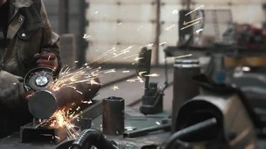 Metal fabrikasında çalışan bir işçi metali işliyor. Metal kıvılcımları ağır sanayi fabrikasında üretiliyor. Metal öğütme işlemi. Çelik fabrikası..