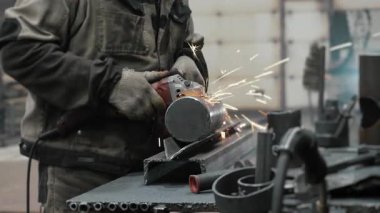 Metal fabrikasında çalışan bir işçi metali işliyor. Metal kıvılcımları ağır sanayi fabrikasında üretiliyor. Metal öğütme işlemi. Çelik fabrikası..