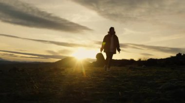 Sırt çantalı genç bir turistin silueti gün batımında dağların arka planında yürüyordu..