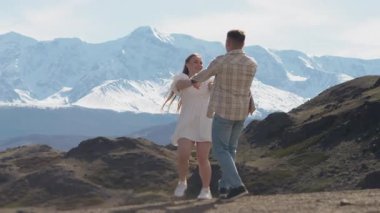 Birbirine aşık iki genç turist el ele tutuşup kar kaplı dağların ve birbirlerinin güzel manzarasının tadını çıkarıyorlar..