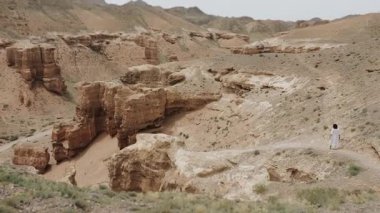Beyaz elbiseli kadın turist Red Rock Kanyonu 'nda uçurumun kenarına yürüyor ve inanılmaz kırmızı kaya manzarasının tadını çıkarıyor..