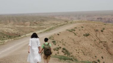 İki turist, sırtında sırt çantası olan küçük bir çocukla bir anne, bir uçurumun kenarında el ele yürürler ve ulusal parktaki güzel bir kanyonun manzarasının tadını çıkarırlar..