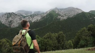 Sırt çantalı bir erkek gezgin yüksek dağların güzel manzaralı dağlık bir alanda yürüyor..