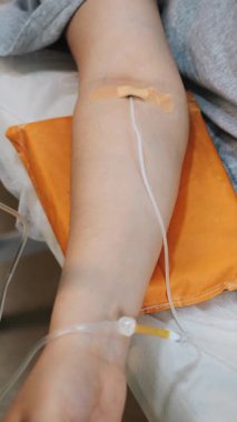Modern bir tıp kliniğinde kadın elinin bir damla ilaçla yakın çekimi. Hastanedeki bir hastaya damardan ilaç verilmesi. Dikey video.