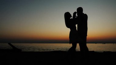Gün batımında sahilde dans eden aşık genç bir çiftin silueti. Adam danstaki kızı döndürüyor. Okyanus kıyısında yeni evlilerin balayı.