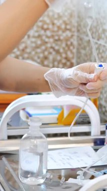 Modern klinikteki hastalar için damar yolu hazırlayan koruyucu eldivenler takan doktorların yakın çekimi. Hastanedeki bir hastaya damardan ilaç verilmesi. Dikey video.