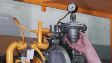 Gaz dağıtım sistemini inceleyen bir mühendisin yakın çekimi. Bir mühendis boru bağlantılarının güvenliğini kontrol ediyor..