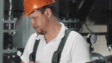 İş üniformalı bir mühendis veya fabrika işçisi dijital tablet kullanır. Bir mühendis fabrikadaki üretim sürecini analiz etmek için bir bilgisayar tableti kullanır..