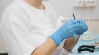 Kadın dişçilerin yakın çekimleri koruyucu eldivenler takarak steril diş aletleriyle paketi açarlar. Modern diş sağlığı kliniği.