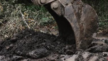 Close-up of an excavator bucket digging a trench to lay utilities and pipes underground.