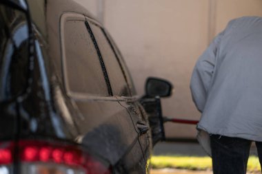 Genç bir adam araba yıkamada yüksek basınçlı suyla araba yıkar. Araba yıkama, yüksek basınçlı su basıncı, araba yıkama, araba yıkama.