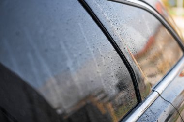 Araba penceresinin arka penceresinde damlalar ve yağmur damlaları var.