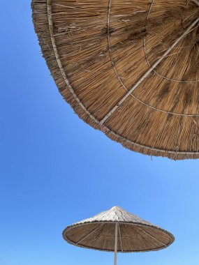 Mavi gökyüzü arka planında saman şemsiyeler