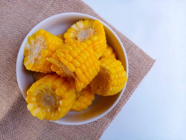 Tatlı mısır koçanları beyaz tabakta yarıya iniyor. 